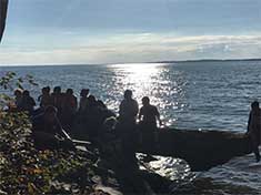 children sitting on a rocky shoreline